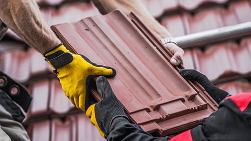 Deux professionnels de MK-Couverture88 tenant une tuile de toiture rouge