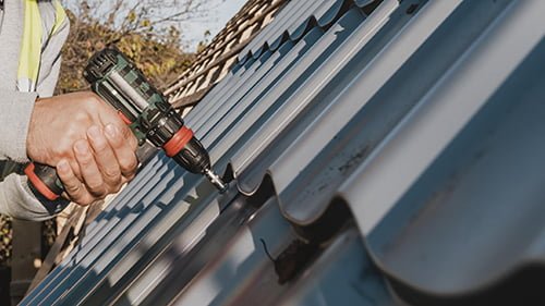 Professionnel de MK-Couverture88 utilisant une perceuse sur un toit métallique
